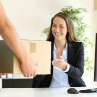 Happy businesswoman receiving a package sitting on a desk at office